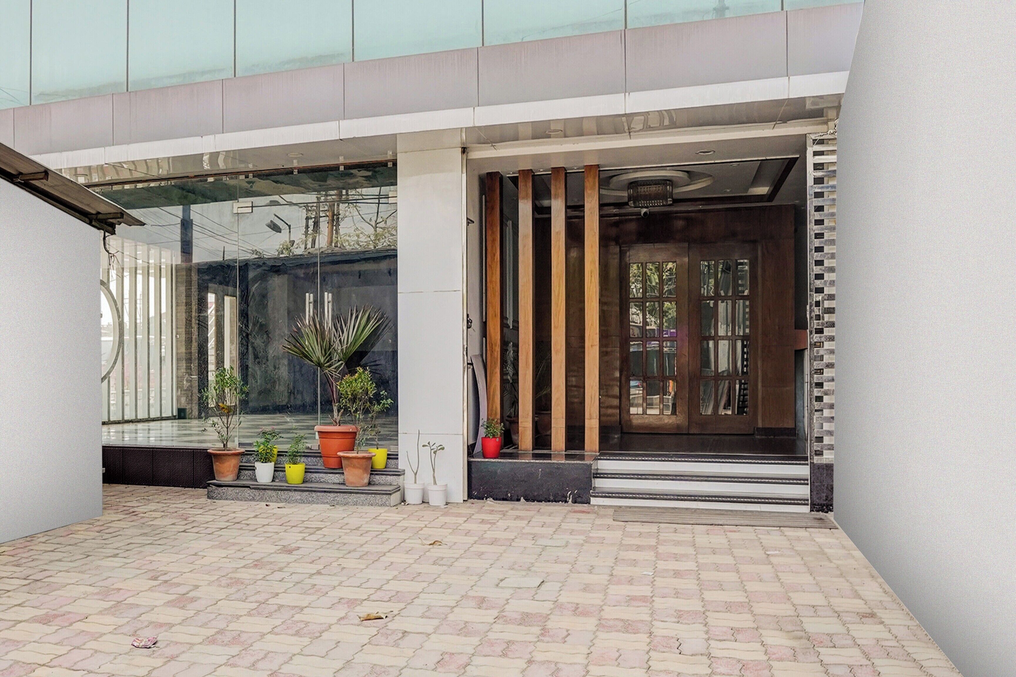 A building entrance with a glass facade, potted plants, and a wooden door.