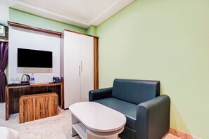 Habitació amb escriptori, cadira, televisió penjada a la paret i armari.