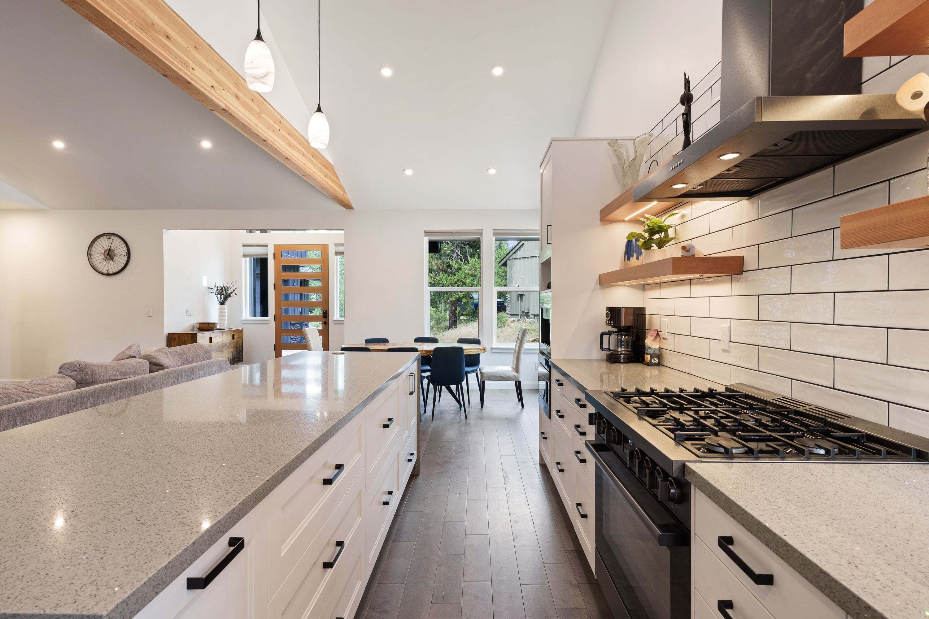 A modern kitchen with a central island, a dining area, and a view of the outdoors.