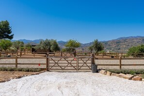 A fenced outdoor area with a gate, gravel ground, and trees. - Guesthouse 'Casita Chupito' with Mountain Views, Wi-Fi and Air Conditioning (Alozaina)