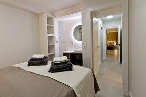 A hotel room with a bed, a bathroom with a sink and mirror, and a hallway leading to another room. - Guesthouse 'Casita Chupito' with Mountain Views, Wi-Fi and Air Conditioning (Alozaina)