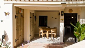 A patio area with a wooden table and chairs, a tiled floor, and a door leading to an interior space. - Guesthouse 'Casita Chupito' with Mountain Views, Wi-Fi and Air Conditioning (Alozaina)