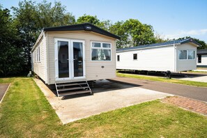 A mobile home with a sliding door, a small porch, and a paved driveway. - Cosy Modern 2-Bed Caravan Near Skegness Beach (Skegness)