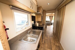 Una cocina compacta con un lavamanos, estufa y alacenas.