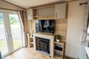 Una sala moderna con una televisión de pantalla plana, una chimenea y muebles de madera.