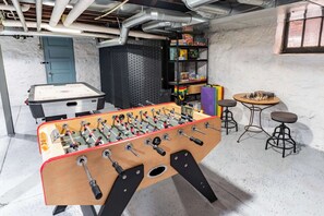 A room with a foosball table, a bookshelf, and a chess table.