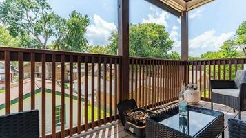 A covered outdoor area with a table and chairs, a grill, and a view of a residential neighborhood.