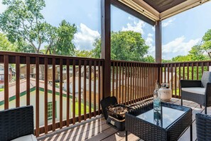 A covered outdoor area with a table and chairs, a grill, and a view of a residential neighborhood.