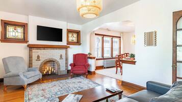 A living room with a fireplace, a television, and a dining area with a view.