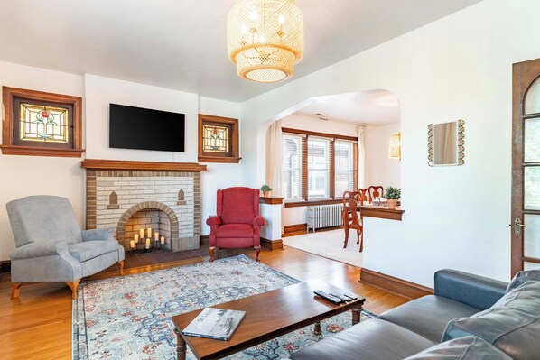 A living room with a fireplace, a television, and a dining area with a view.