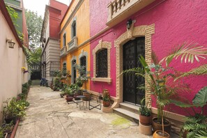 A narrow alley with a row of colorful buildings, potted plants, and outdoor seating. - Chic 3-bedroom townhouse in heart of Roma Norte (Ciudad de México)