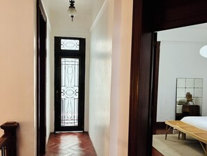 A hallway with a wooden door leading to a room with a bed and a small table. - Chic 3-bedroom townhouse in heart of Roma Norte (Ciudad de México)