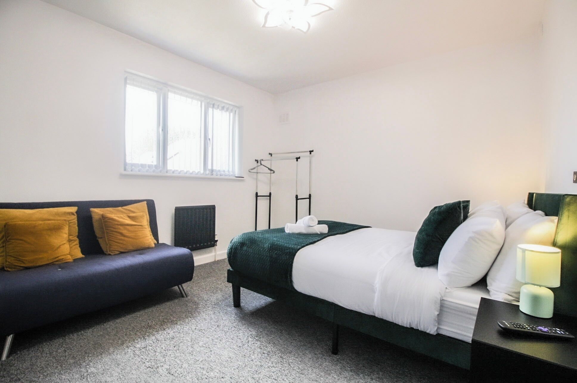 Ein Schlafzimmer mit einem Bett, einer Couch, einem Heizkörper und einem Fenster.