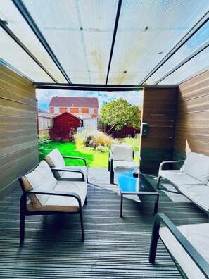 An enclosed patio with a view of a residential area, featuring a sofa, chairs, and a table. - Hockley 4-bed, Sleeps 12 w/ Garden & Free Parking (Birmingham)