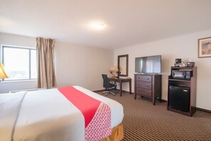 A hotel room with a bed, desk, chair, television, and a microwave. - King Bed Accessible Non-Smoking (Houston)
