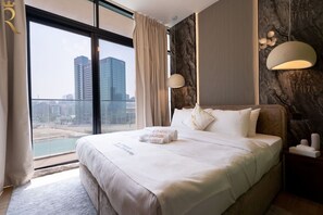 Ein Hotelzimmer mit einem großen Bett, Blick auf die Stadt und einer modernen Lampe.