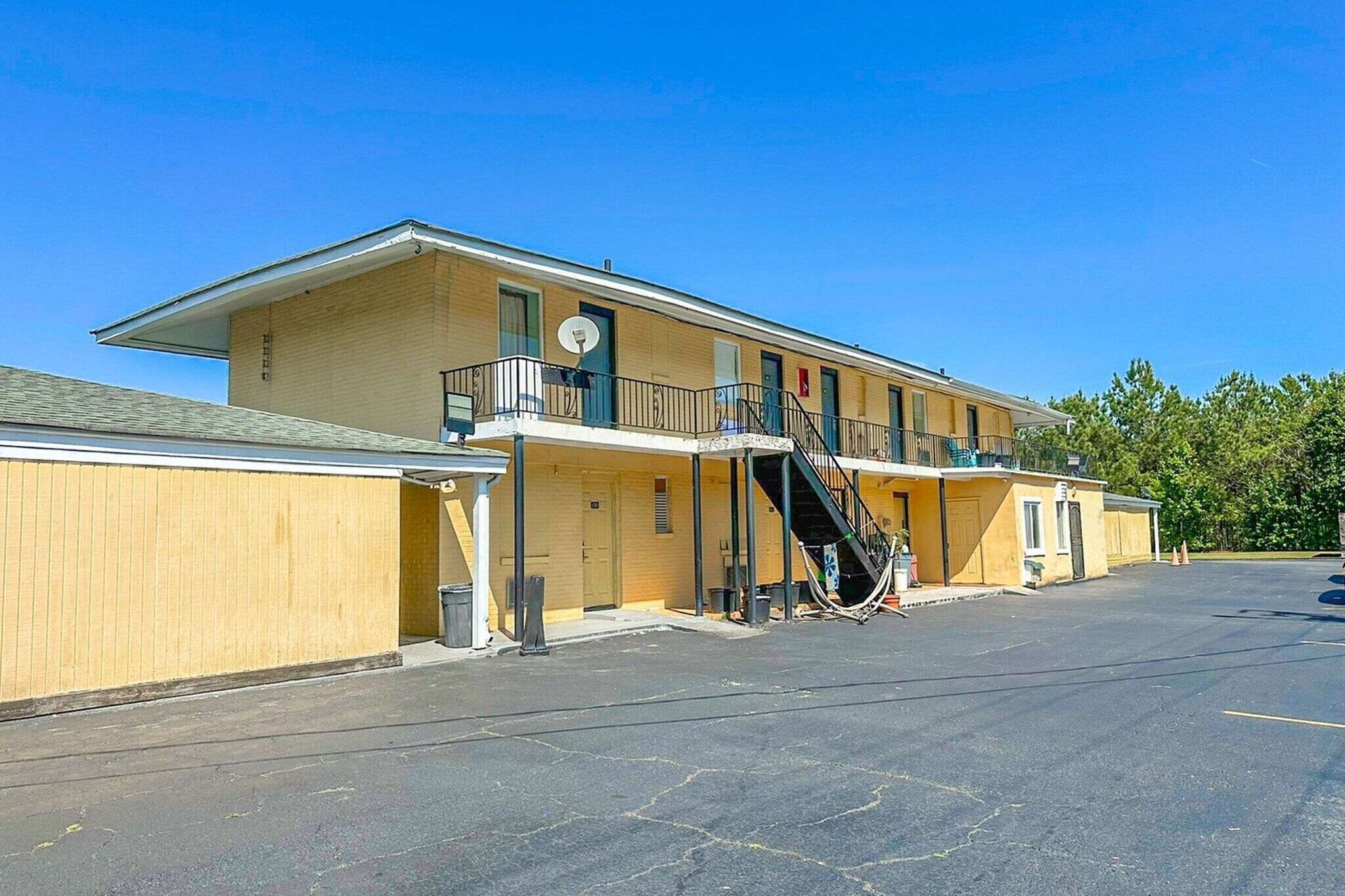 Un motel composé d’un bâtiment à deux étages, d’un espace de stationnement couvert et d’un escalier menant à l’étage supérieur.