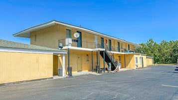 Un motel composé d’un bâtiment à deux étages, d’un espace de stationnement couvert et d’un escalier menant à l’étage supérieur.