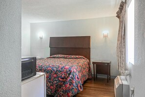 A bedroom with a bed, bedside table, and a heater.