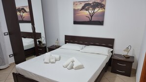 A neatly made bed with towels, a bedside lamp, and a painting of a tree on the wall. - Villa Giusy: Pool and Relaxation in Salento (Galatina)
