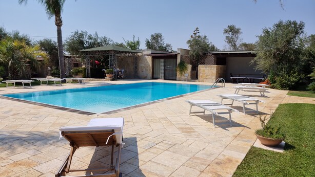 A swimming pool with lounge chairs, a covered seating area, and a stone patio. - Villa Giusy: Pool and Relaxation in Salento (Galatina)