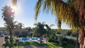 A pool area with a clear view of the surrounding landscape, including palm trees and a well-maintained lawn. - Villa Giusy: Pool and Relaxation in Salento (Galatina)