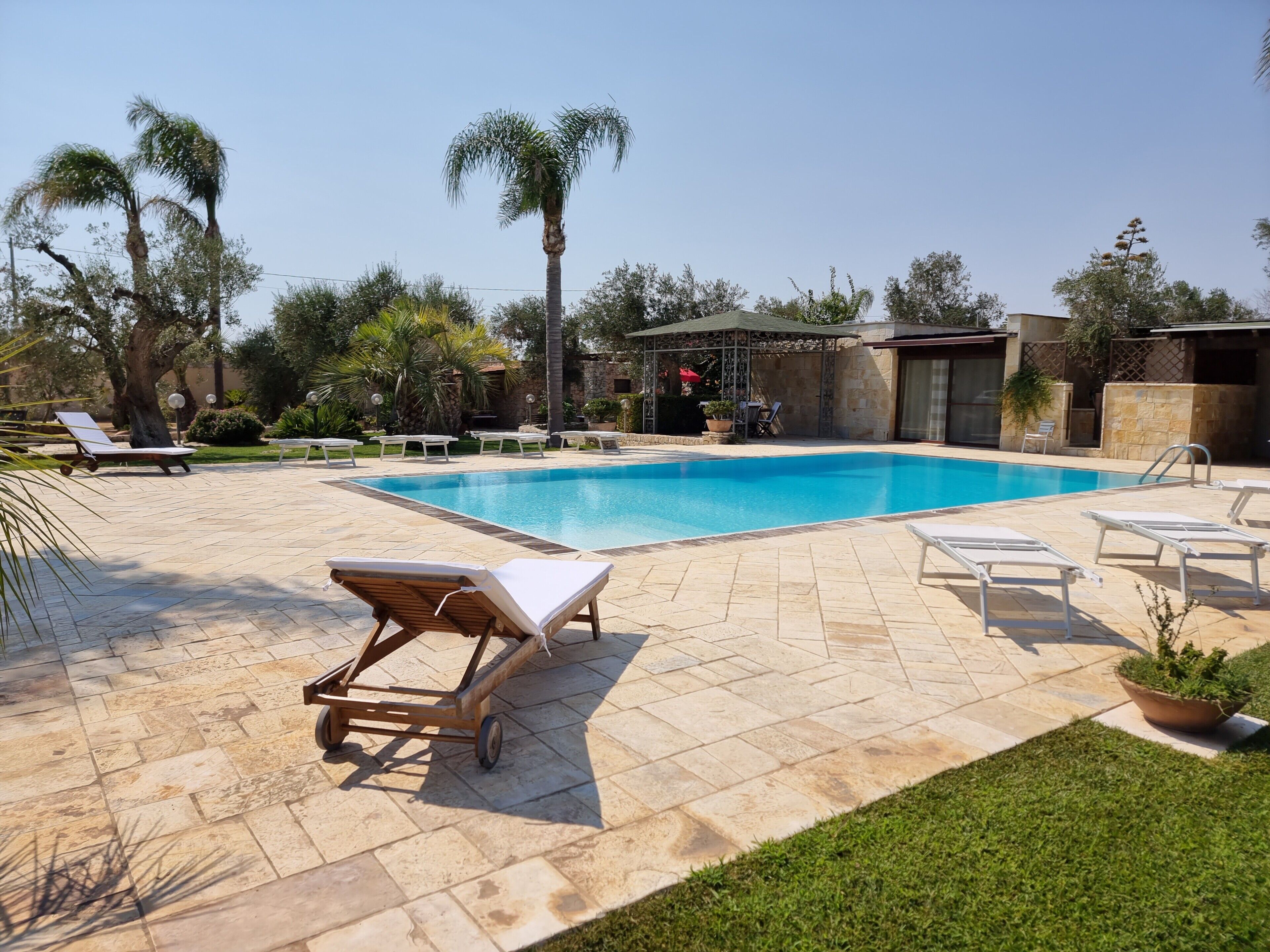 Una piscina con lettini e un gazebo.
