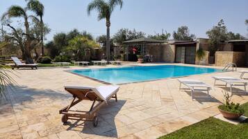 Una piscina con lettini e un gazebo.