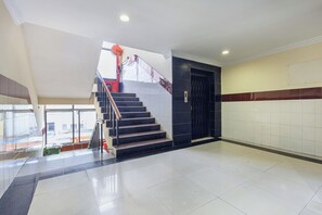 Una escalera con barandilla, una puerta y suelo de baldosas.
