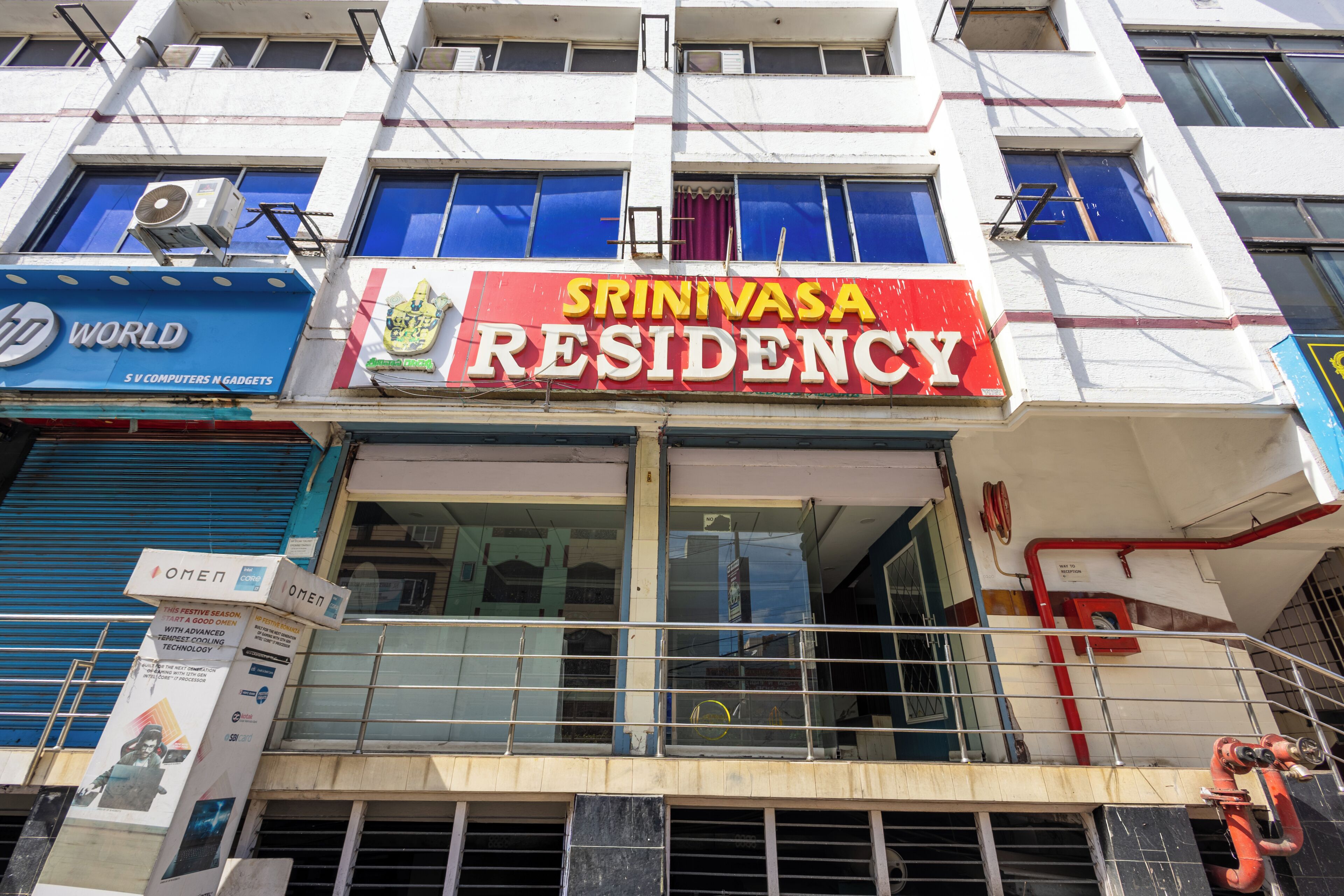 Un edificio con un letrero que dice 'Srinivasa Residency' y otro letrero que dice 'HP World'.