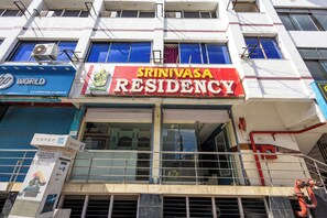 Un immeuble avec une enseigne indiquant « Srinivasa Residency » et une autre indiquant « HP World ».