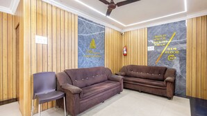 A reception area with two sofas, a chair, a ceiling fan, and a fire extinguisher. - SRINIVASA RESIDENCY (Tirupati)