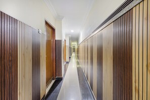 Un couloir aux murs recouverts de lambris en bois, qui mène à une porte au fond.