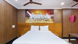 A hotel room with a large bed, wooden panel walls, a ceiling fan, and a mural of horses. - SRINIVASA RESIDENCY (Tirupati)