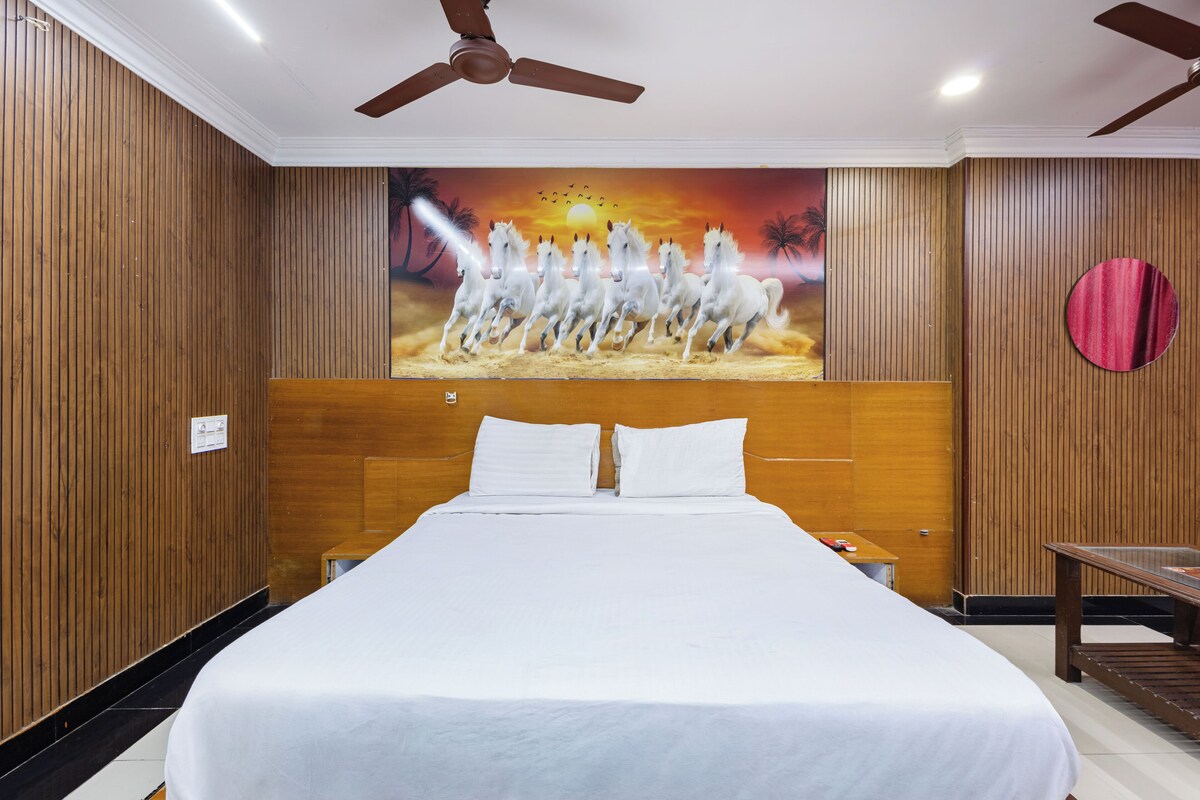 Habitación de hotel con una cama grande, paneles de madera, ventilador de techo y un mural de caballos.