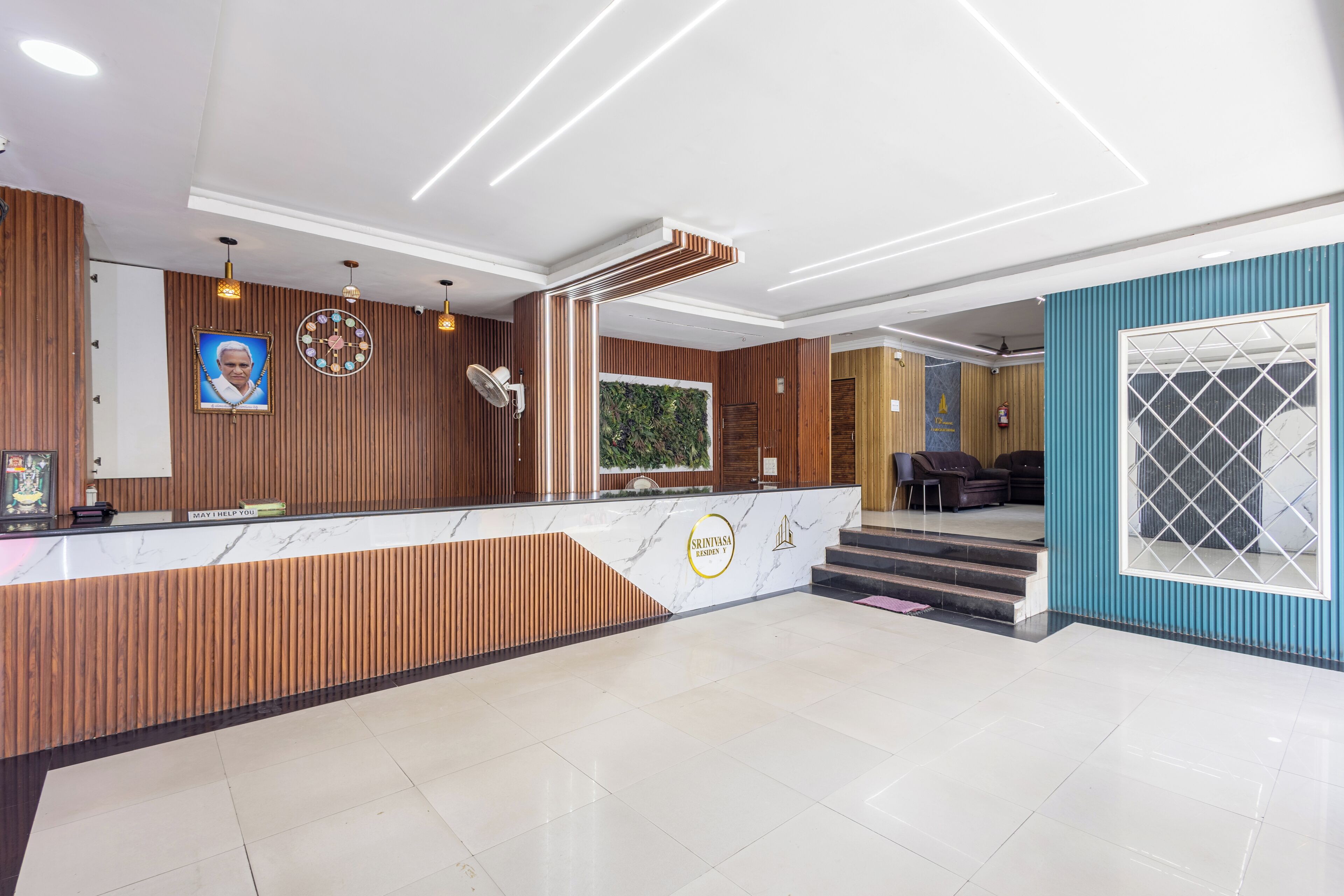 A hotel reception area with a wooden reception desk, a clock, and a seating area with sofas.