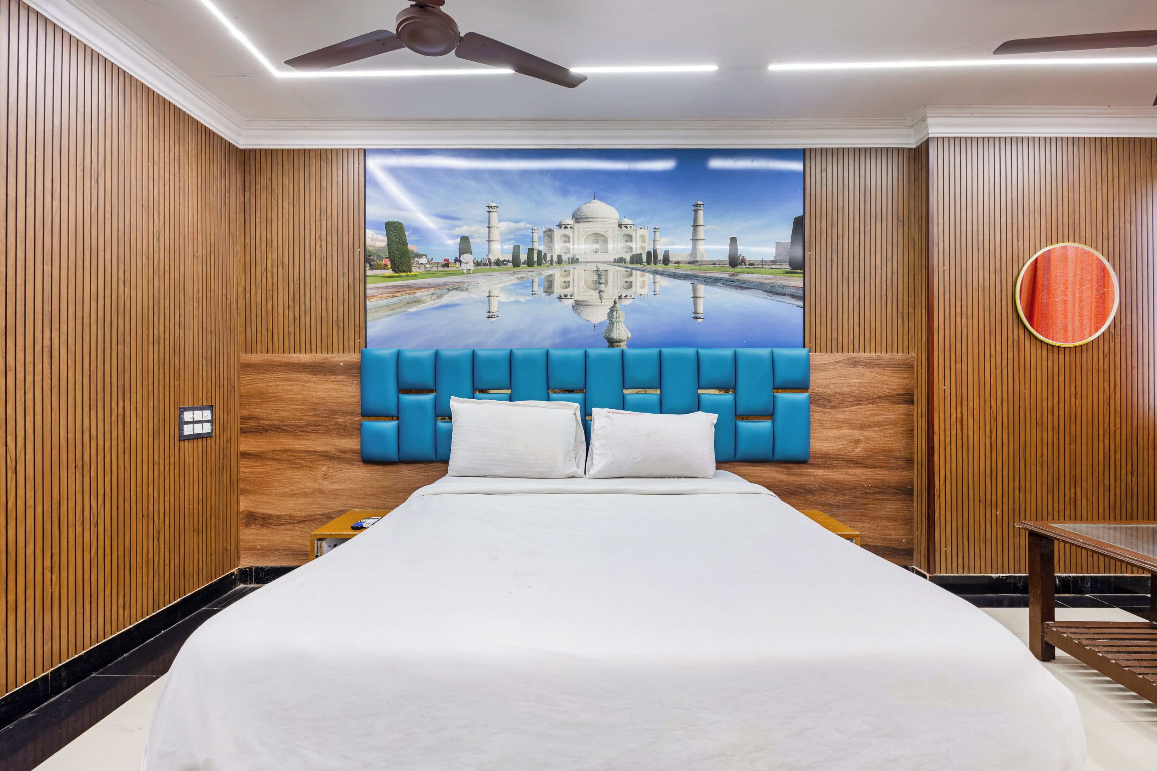 A hotel room with a large bed, a ceiling fan, and a wall mural of a famous monument.