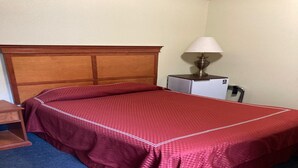 Une chambre d’hôtel avec un lit, une table de chevet avec une lampe et un petit bureau.