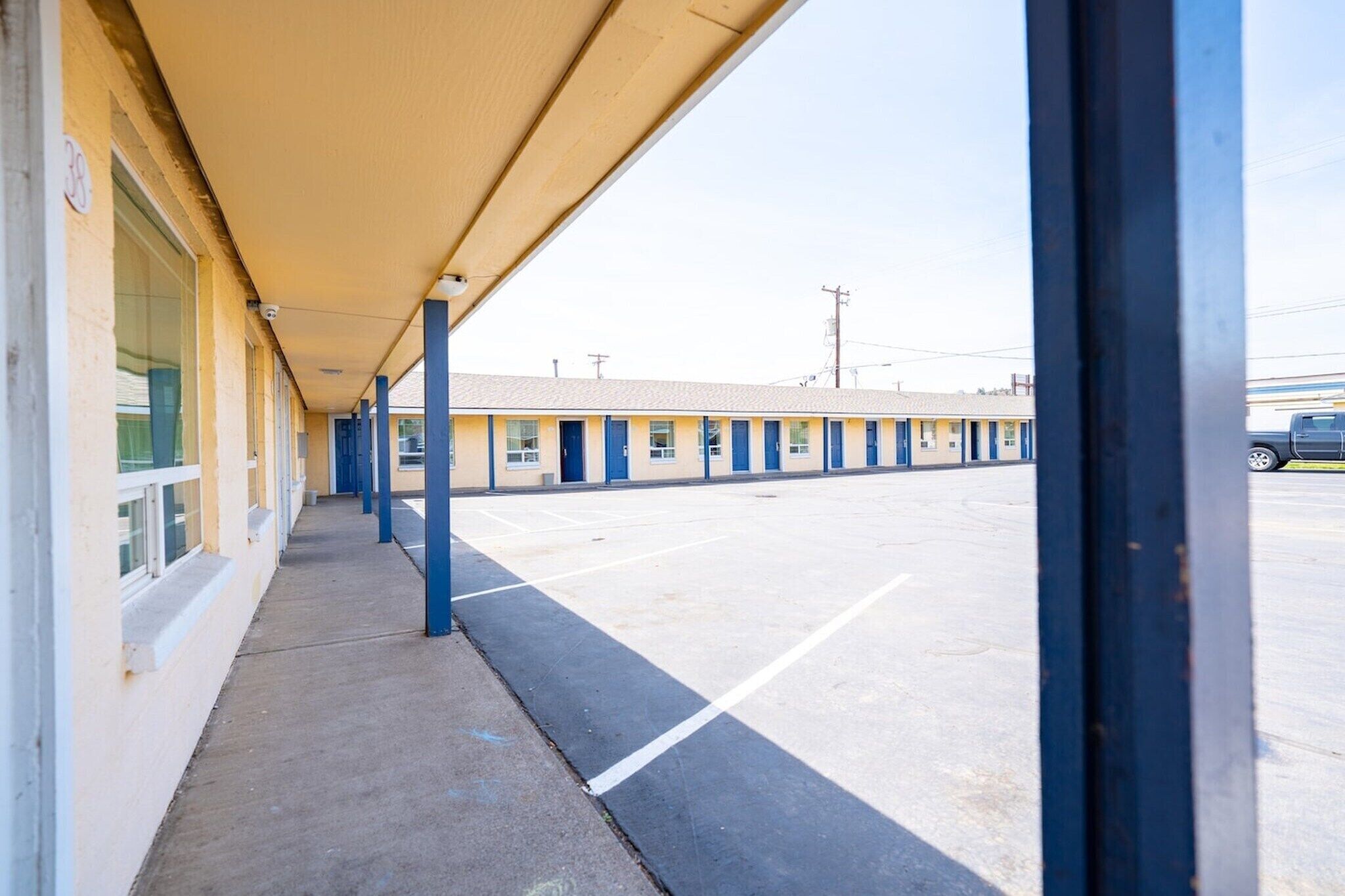 A motel with a covered walkway and a parking lot.