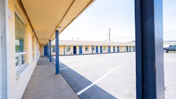 A motel with a covered walkway and a parking lot.