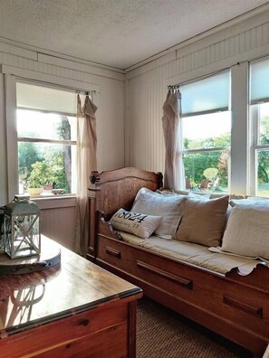 Ein gemütliches Zimmer mit einer Holzbank, einem kleinen Tisch und einem Fenster mit Vorhängen.