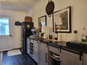 Eine Küche mit Kaffeemaschine, einer Weinflasche und einem gerahmten Bild an der Wand.