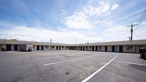 A motel with a parking lot, a row of rooms, and a utility truck. - Premium Queen Bed|Kitchenette (Madras OR)