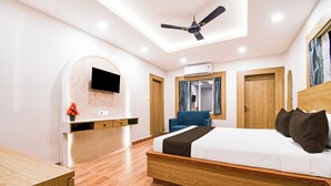 A modern bedroom with a bed, a desk, a TV, and a ceiling fan. - Palette Shree Jagannath Puri (Puri)