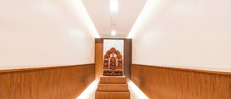 A narrow hallway with wooden paneling and a central staircase leading to a small shrine.