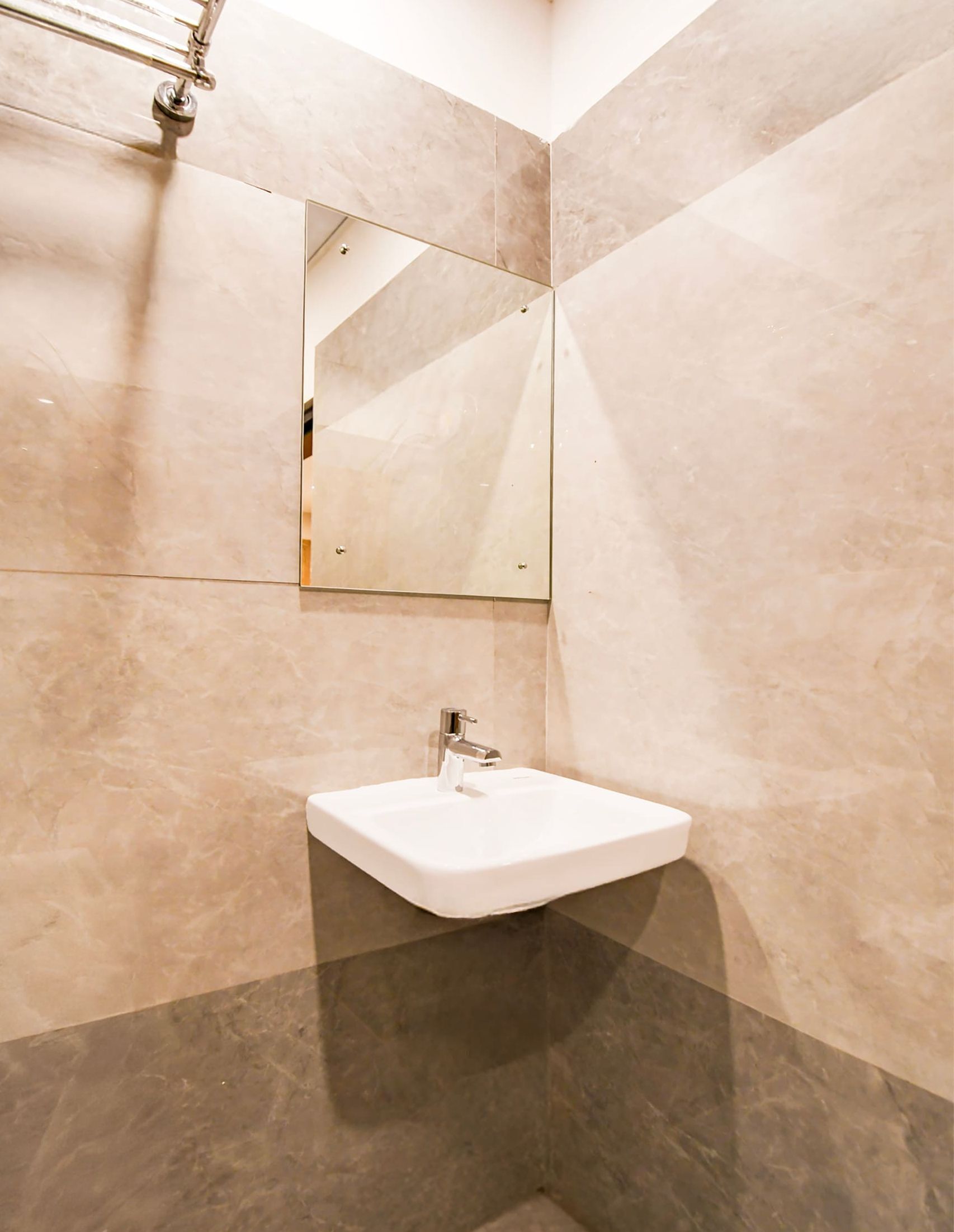 Un baño con un lavamanos blanco, un espejo y paredes cubiertas de azulejos color beige.