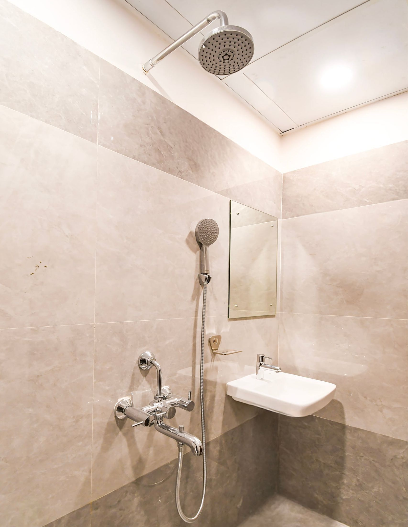 Un baño con ducha, lavamanos y espejo.