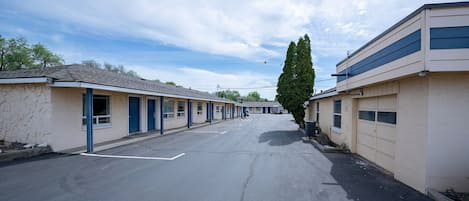 A row of motel buildings with a parking lot in between.