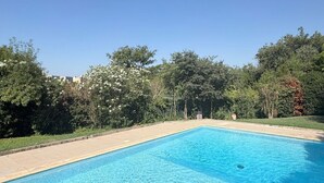 A rectangular swimming pool with clear blue water, surrounded by a tiled deck and lush greenery. - Montpellier Sunlight, Air Conditioning, Pool, and Private Parking (Montpellier)