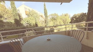 A round table with a patterned tablecloth, metal chairs, and a small decorative item on the table. - Montpellier Sunlight, Air Conditioning, Pool, and Private Parking (Montpellier)